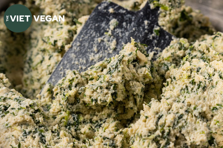 spinach, tofu, and vegan cheese filling for spanakopita, up close with a black spatula